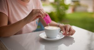 Woman pouring sugar substitute in her coffee