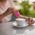 Woman pouring sugar substitute in her coffee