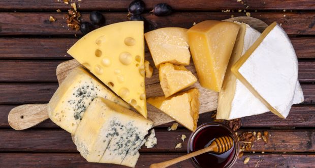 several cheeses on wooden cheese board