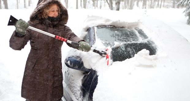 Woman scraping snow off of her car