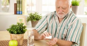 Man taking pill at kitchen table