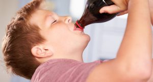 Young boy drinking soda from the bottle