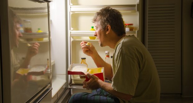 Man eating from refrigerator late at night