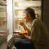 Man eating from refrigerator late at night