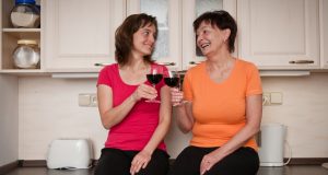 Senior mom and adult daughter drinking red wine together