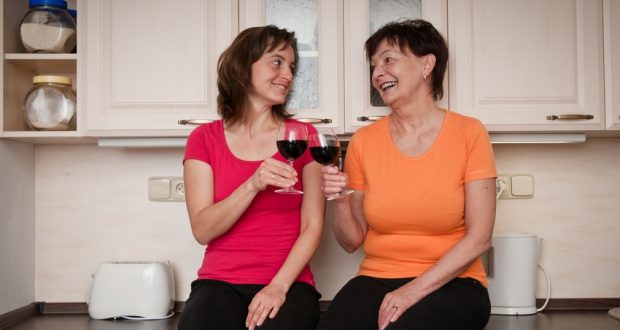 Senior mom and adult daughter drinking red wine together