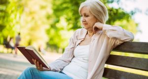 Woman sitting on bench in the park reading a book