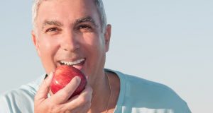 Happy older man eating an apple