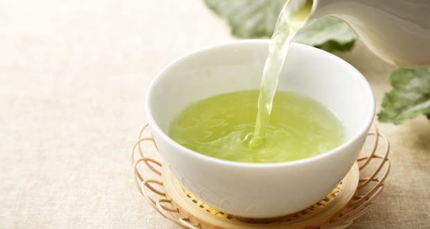 teapot pouring green tea into cup