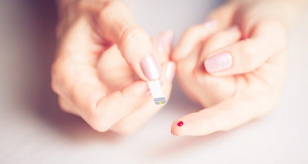 close-up glucose test strip next to finger