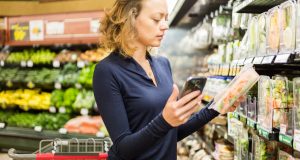 Young woman comparing produce at grocery store