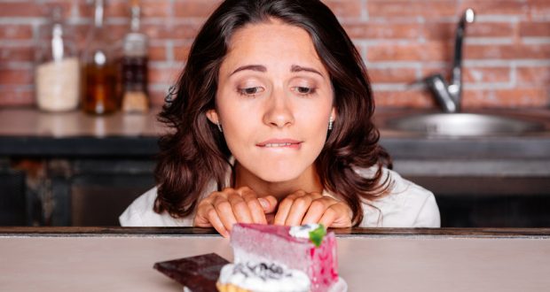 Woman craving piece of cake on a plate