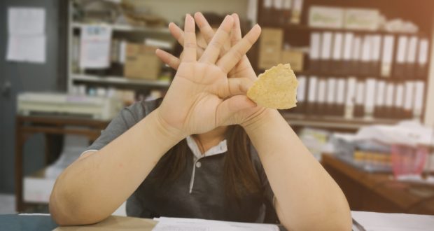 woman eating chips covering her face