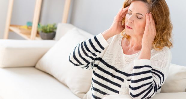 woman with headache sitting on couch